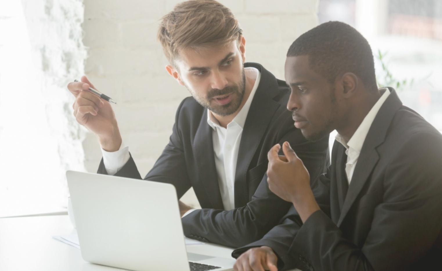 Person reviewing financial documents with calculator and laptop showing budget planning worksheets